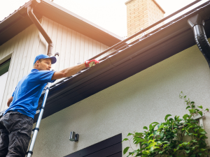 A Columbia roofer cleaning gutters as part of winter roof preparation